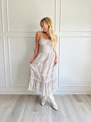 Beige striped midi dress with eyelet detailing and tiered skirt.