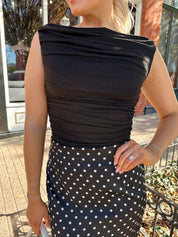 Woman wearing black ruched sleeveless top with polka dot maxi skirt. 