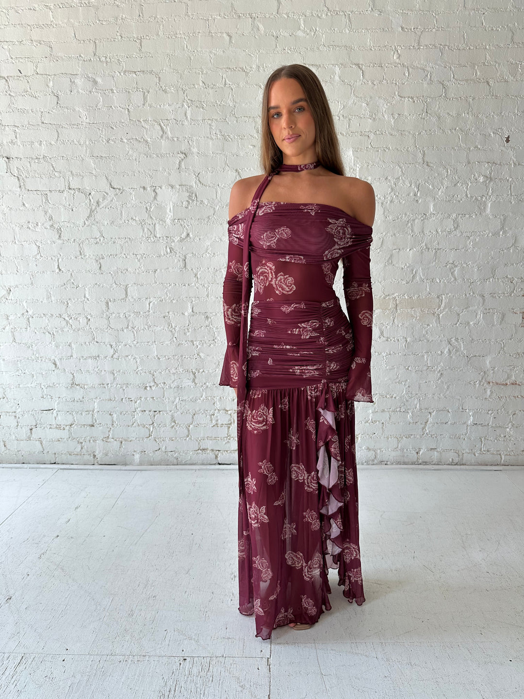 Woman wearing a purple floral mesh maxi dress with an off the shoulder neckline, and detachable scarf. 