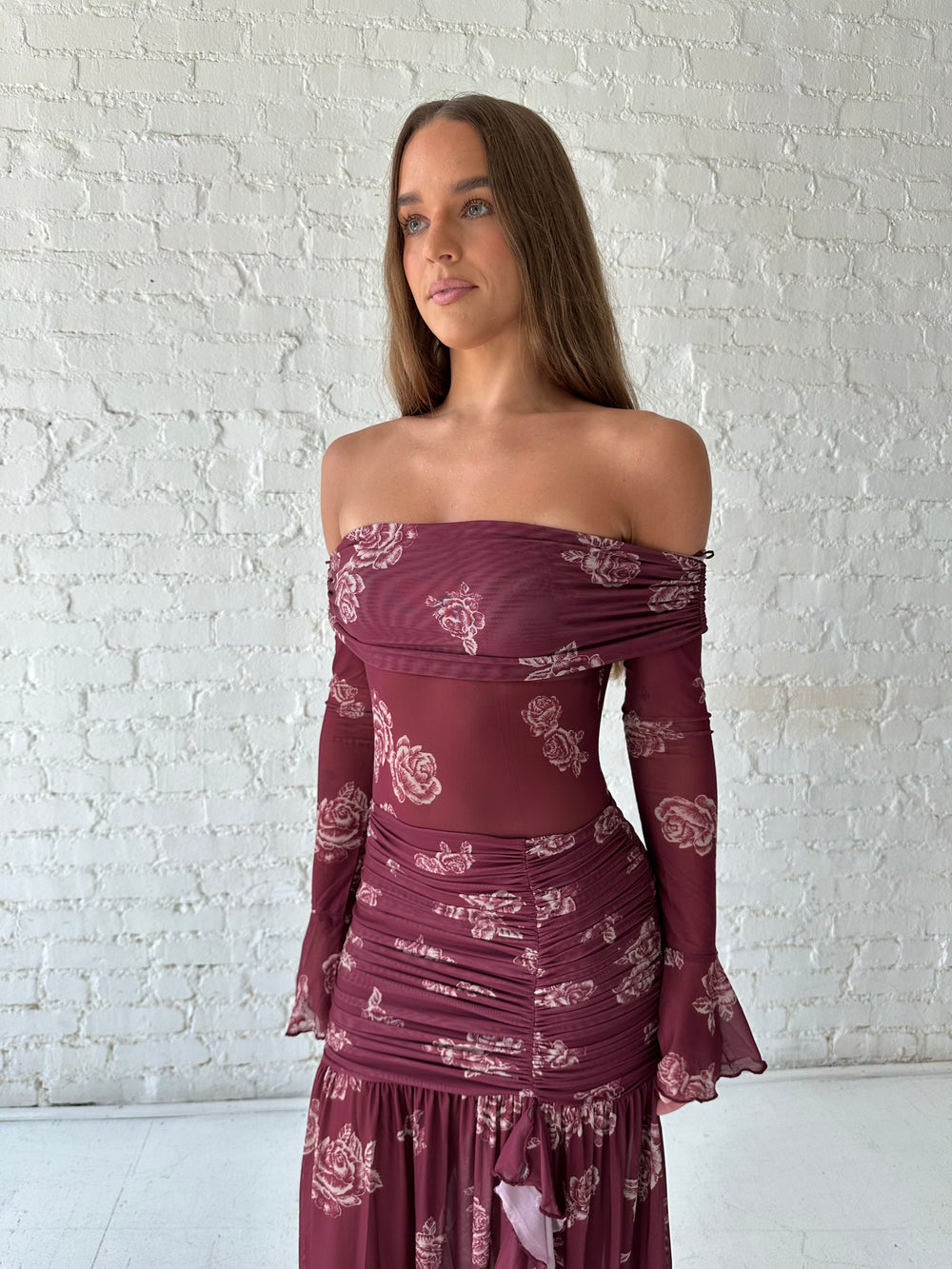 Woman wearing a purple floral mesh maxi dress with an off the shoulder neckline, and detachable scarf. 
