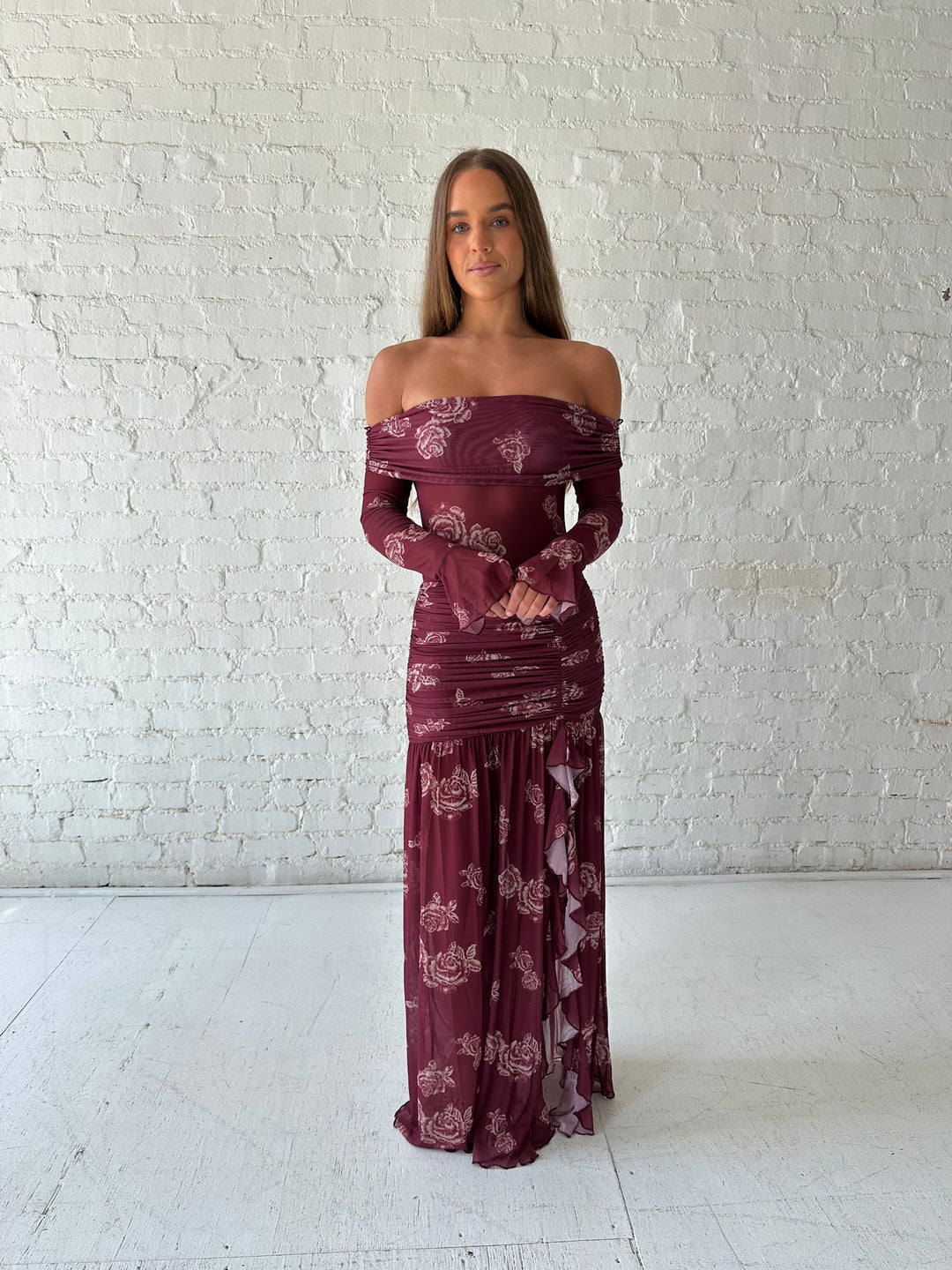 Woman wearing a purple floral mesh maxi dress with an off the shoulder neckline, and detachable scarf. 