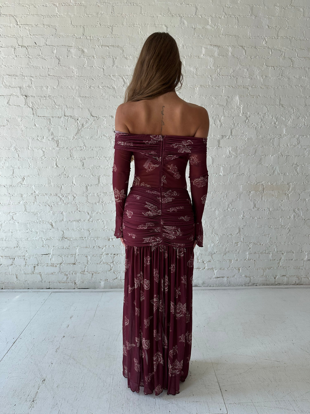 Woman wearing a purple floral mesh maxi dress with an off the shoulder neckline, and detachable scarf. 