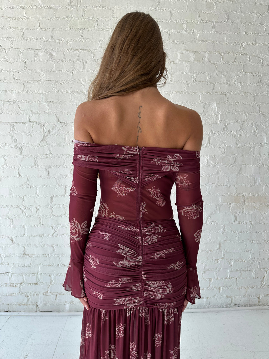 Woman wearing a purple floral mesh maxi dress with an off the shoulder neckline, and detachable scarf. 