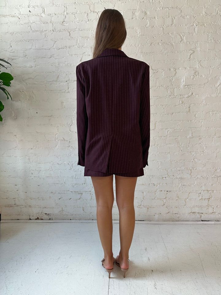 Woman wearing burgundy striped two piece skirt set with oversized blazer top.