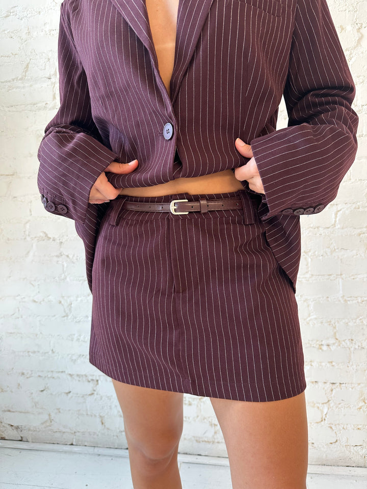 Woman wearing burgundy striped two piece skirt set with oversized blazer top.