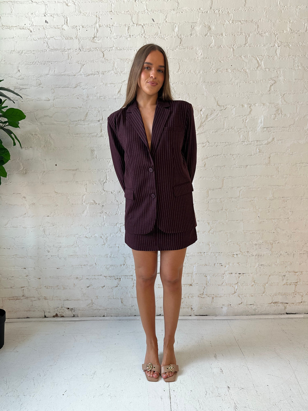 Woman wearing burgundy striped two piece skirt set with oversized blazer top.