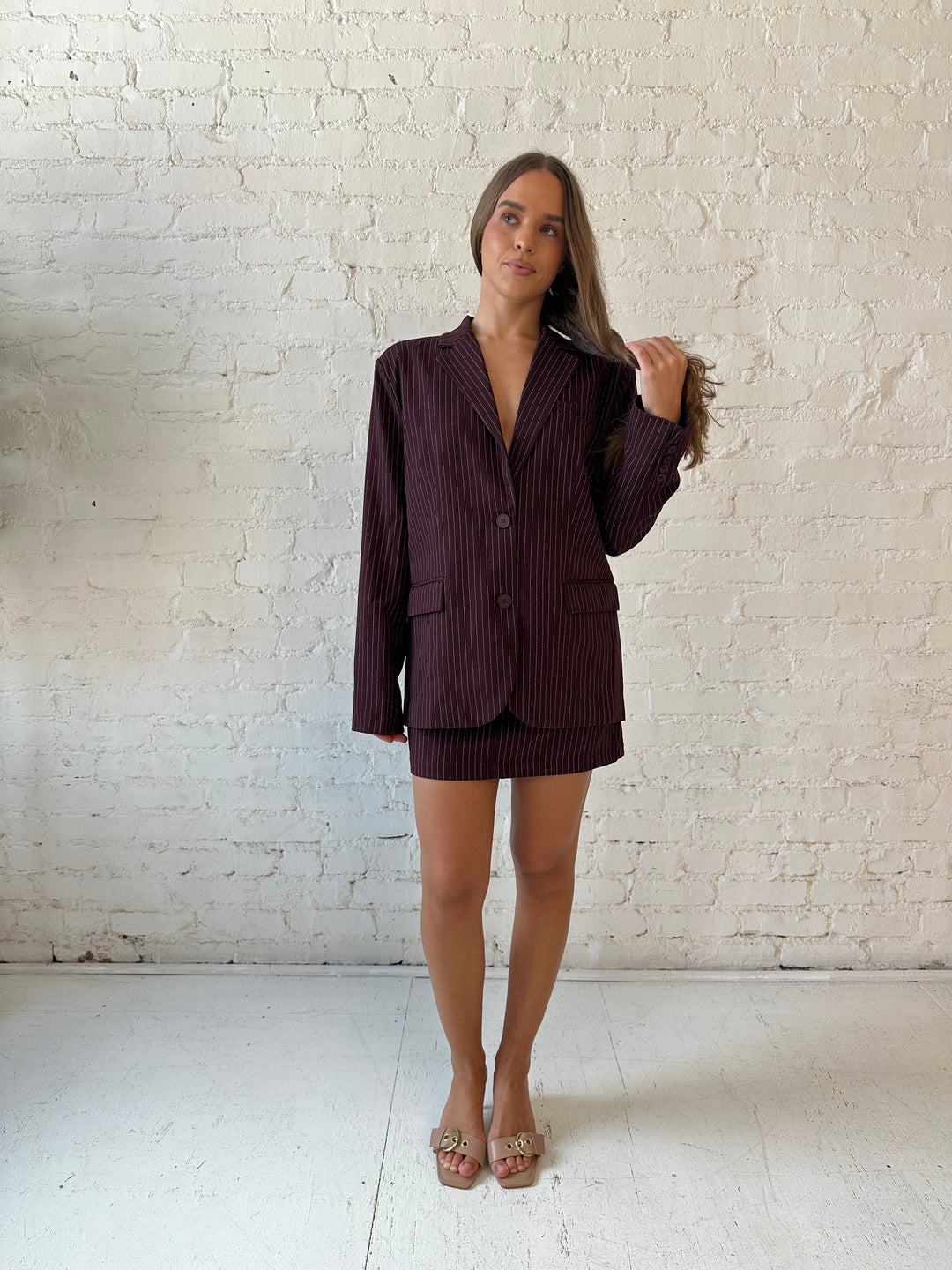 Woman wearing burgundy striped two piece skirt set with oversized blazer top.