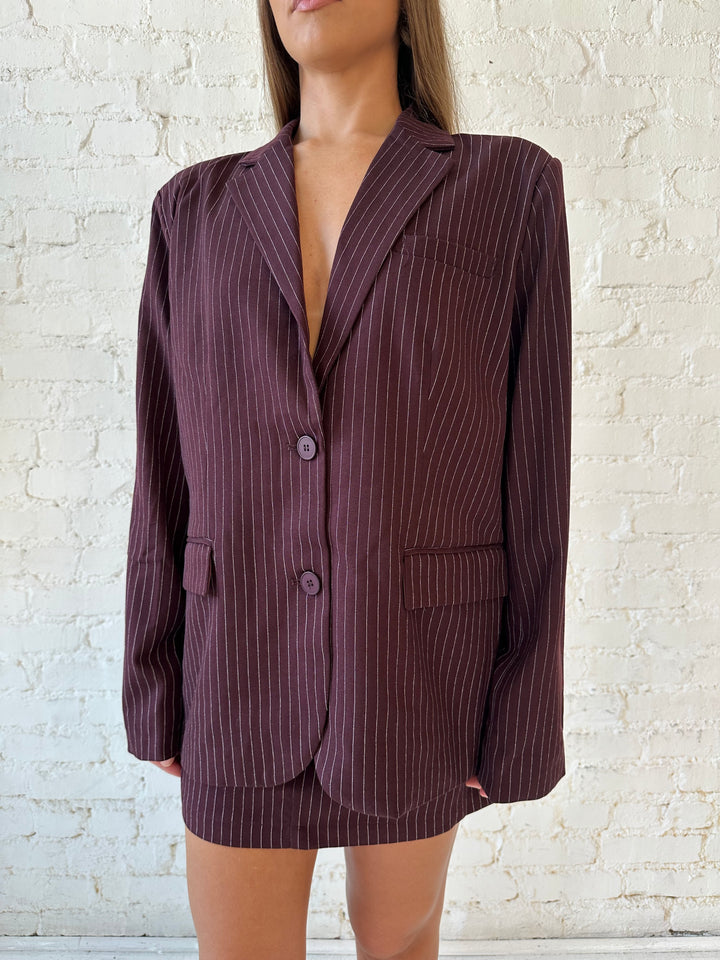 Woman wearing burgundy striped two piece skirt set with oversized blazer top.