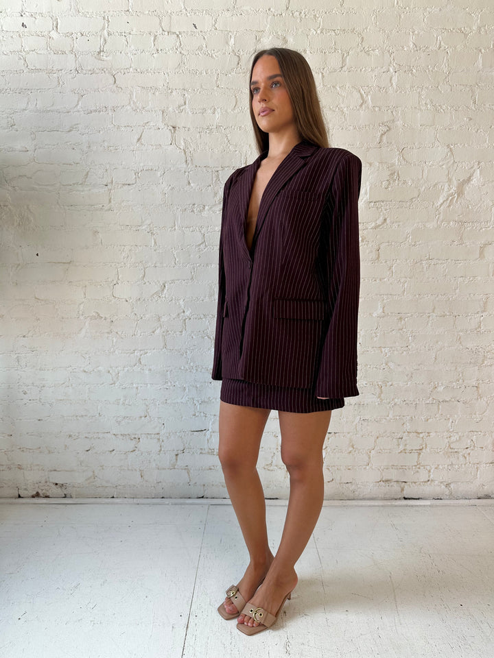 Woman wearing burgundy striped two piece skirt set with oversized blazer top.