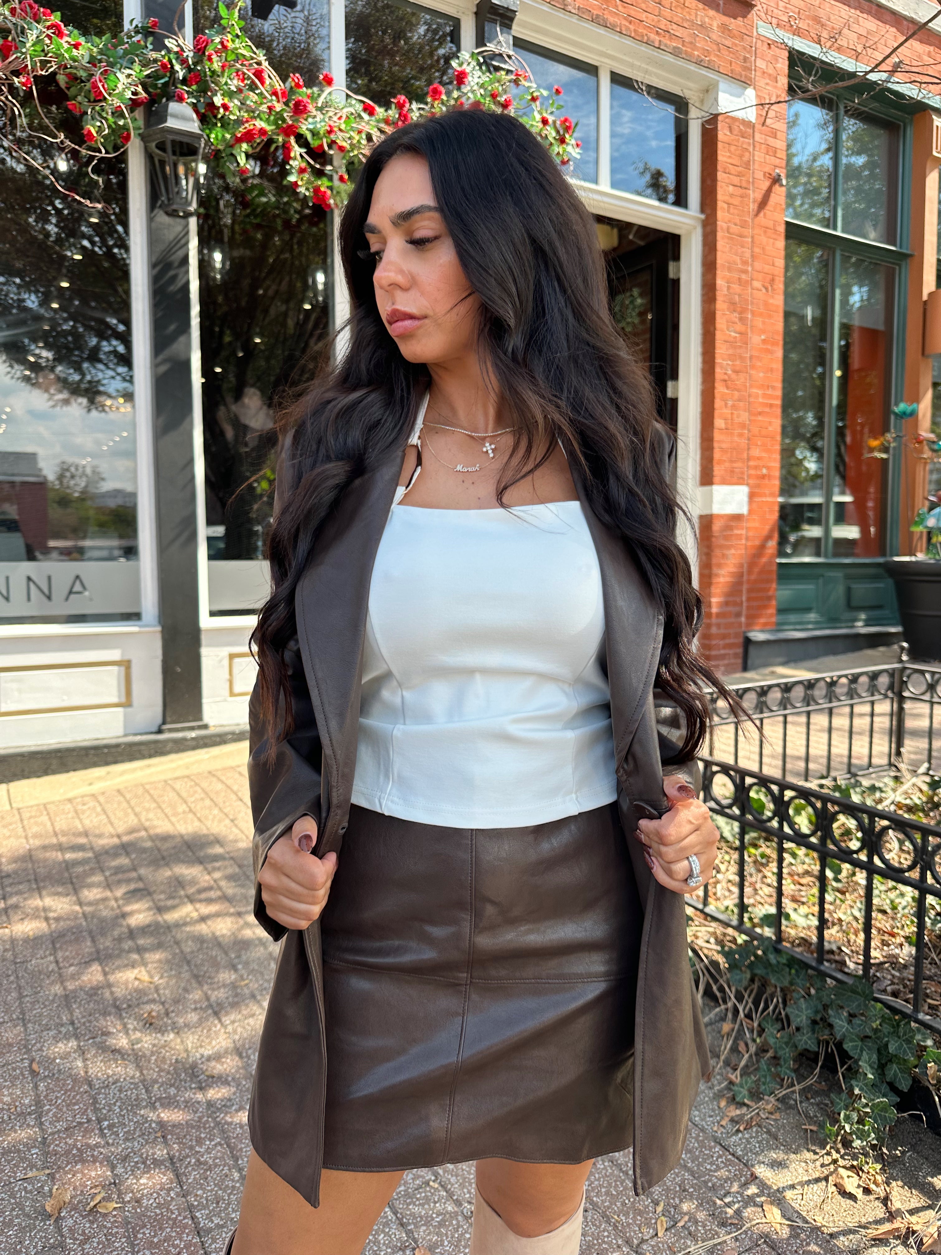Woman wearing brown leather high waisted skirt with matching blazer. 