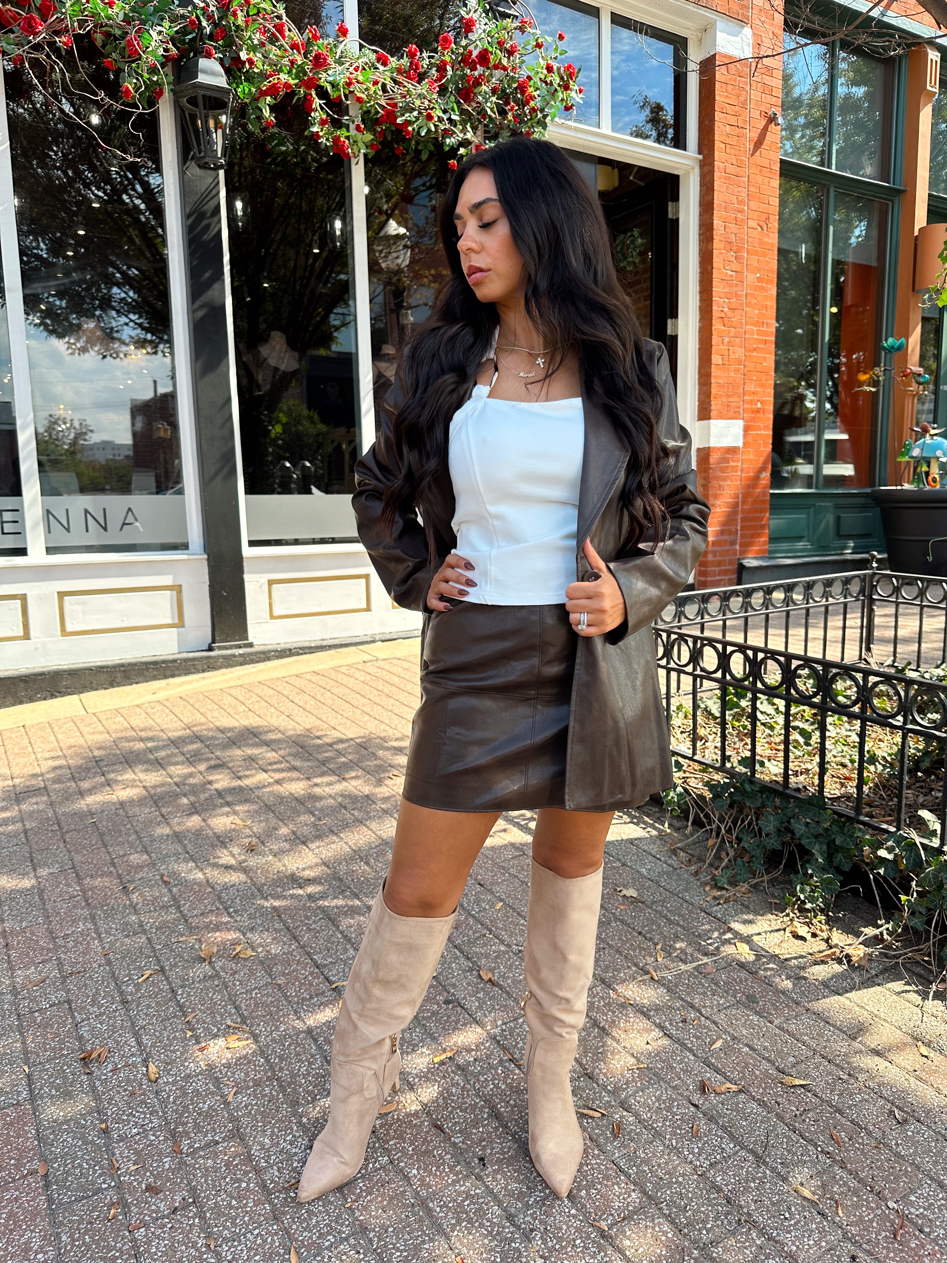 Woman wearing brown leather high waisted skirt with matching blazer. 