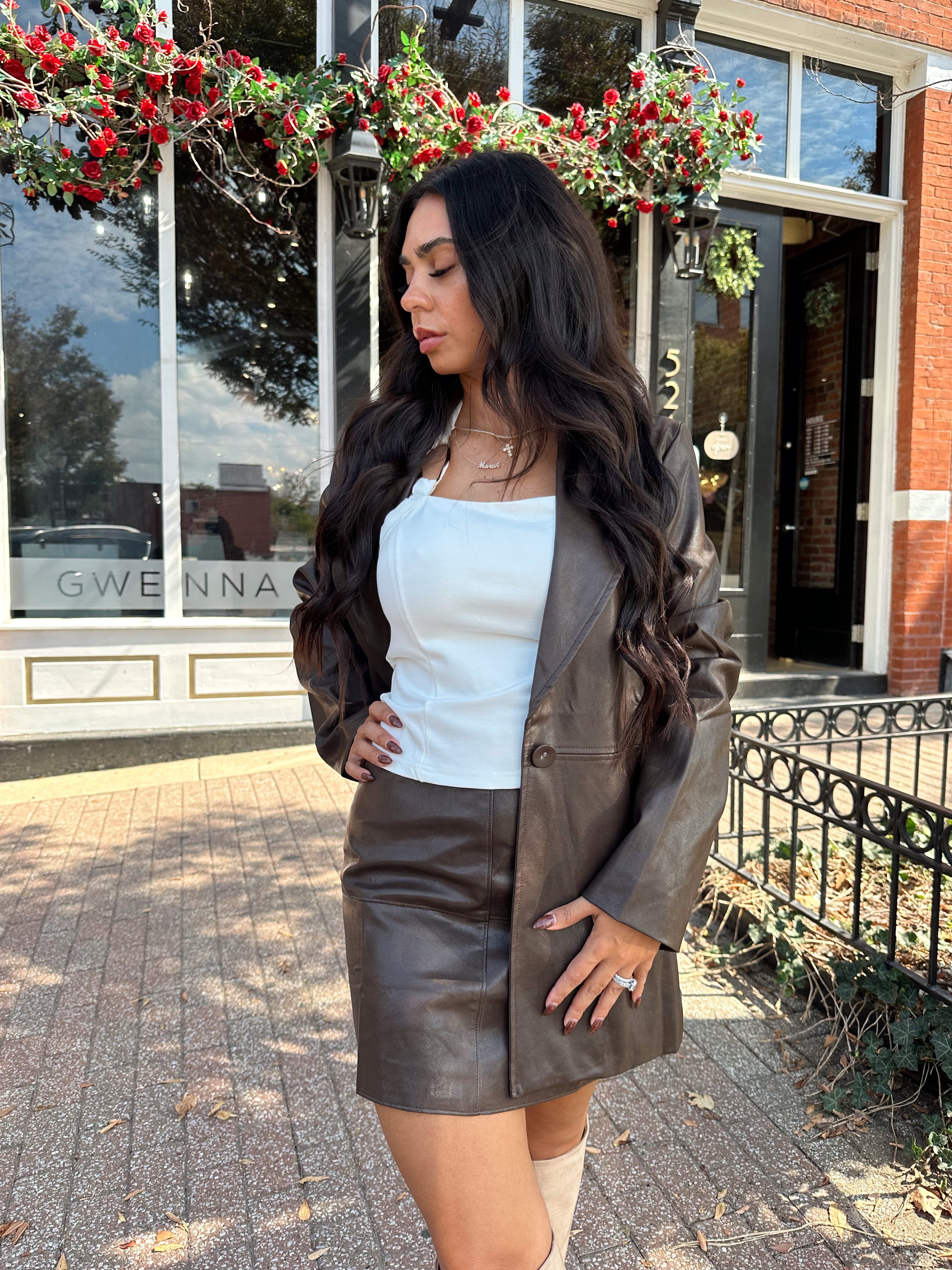 Woman wearing brown leather high waisted skirt with matching blazer. 