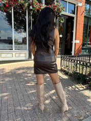 Woman wearing brown leather high waisted skirt with matching blazer. 