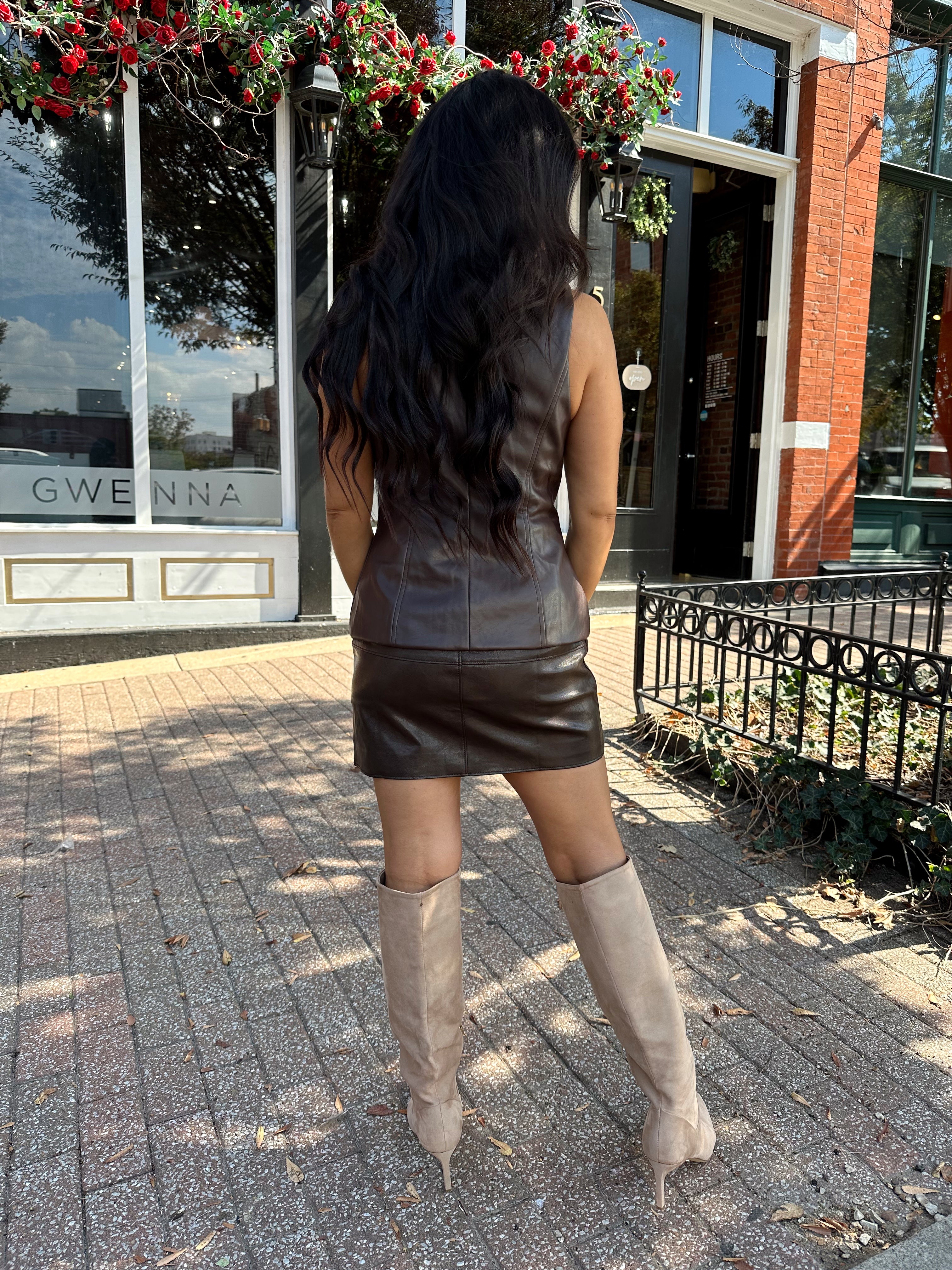 Woman wearing brown leather high waisted skirt with matching blazer. 