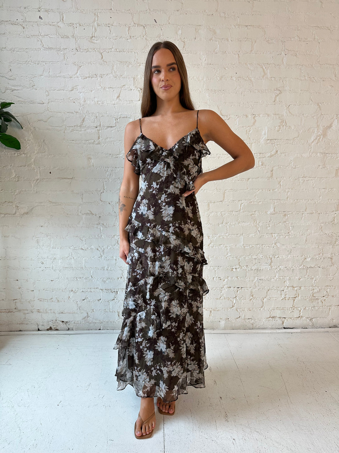 Woman wearing brown floral ruffle tiered maxi dress with adjustable spaghetti straps. 
