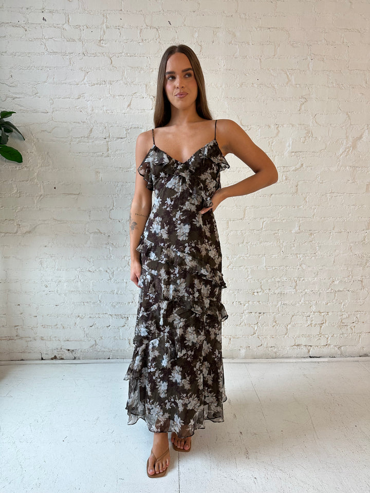 Woman wearing brown floral ruffle tiered maxi dress with adjustable spaghetti straps. 