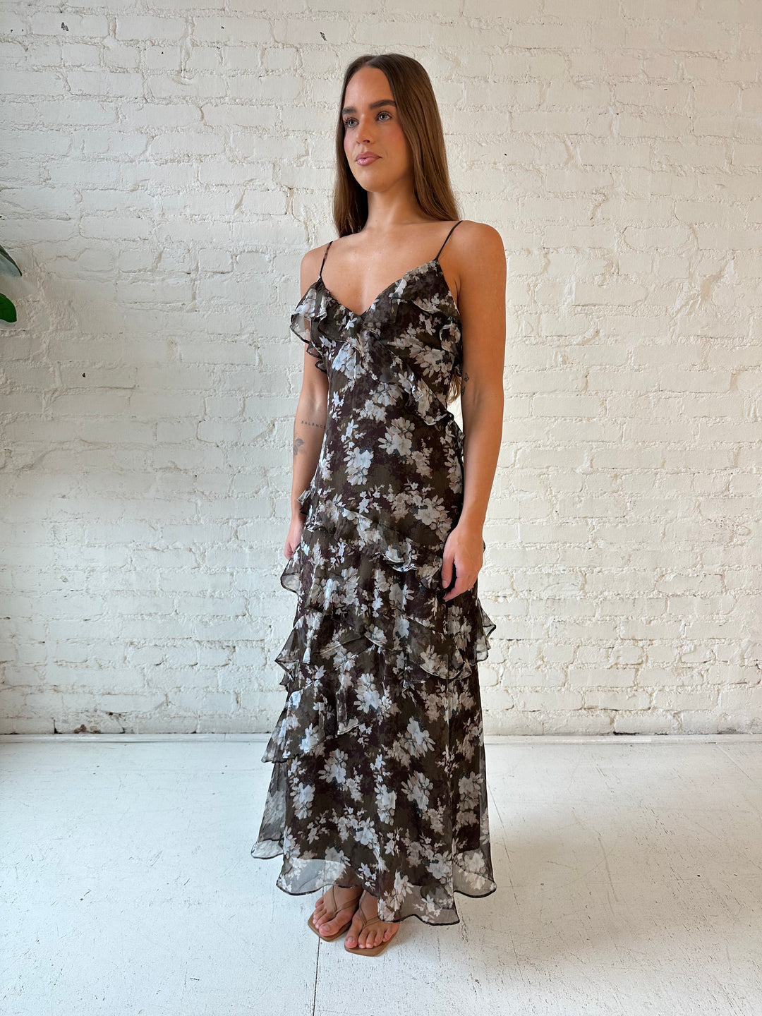 Woman wearing brown floral ruffle tiered maxi dress with adjustable spaghetti straps. 