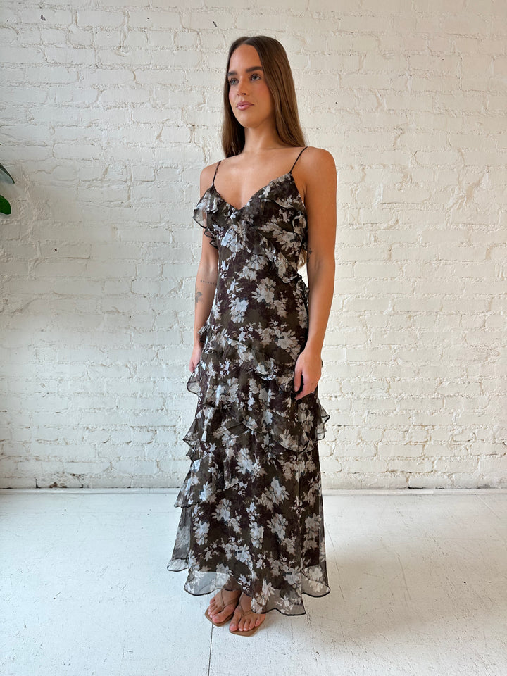 Woman wearing brown floral ruffle tiered maxi dress with adjustable spaghetti straps. 