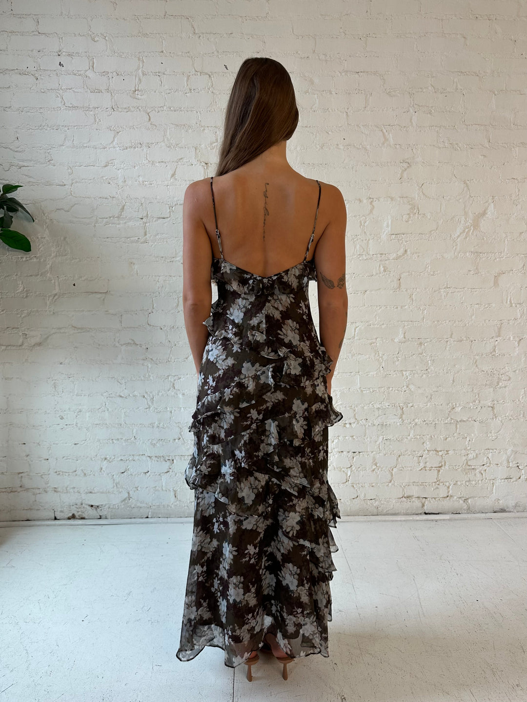 Woman wearing brown floral ruffle tiered maxi dress with adjustable spaghetti straps. 
