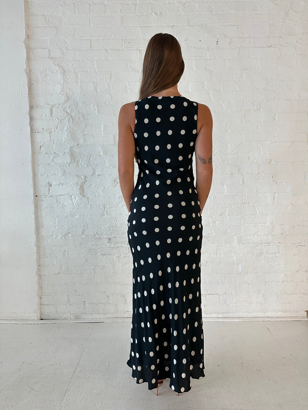 Woman wearing black and white polka dot high neck maxi dress with tan heels.