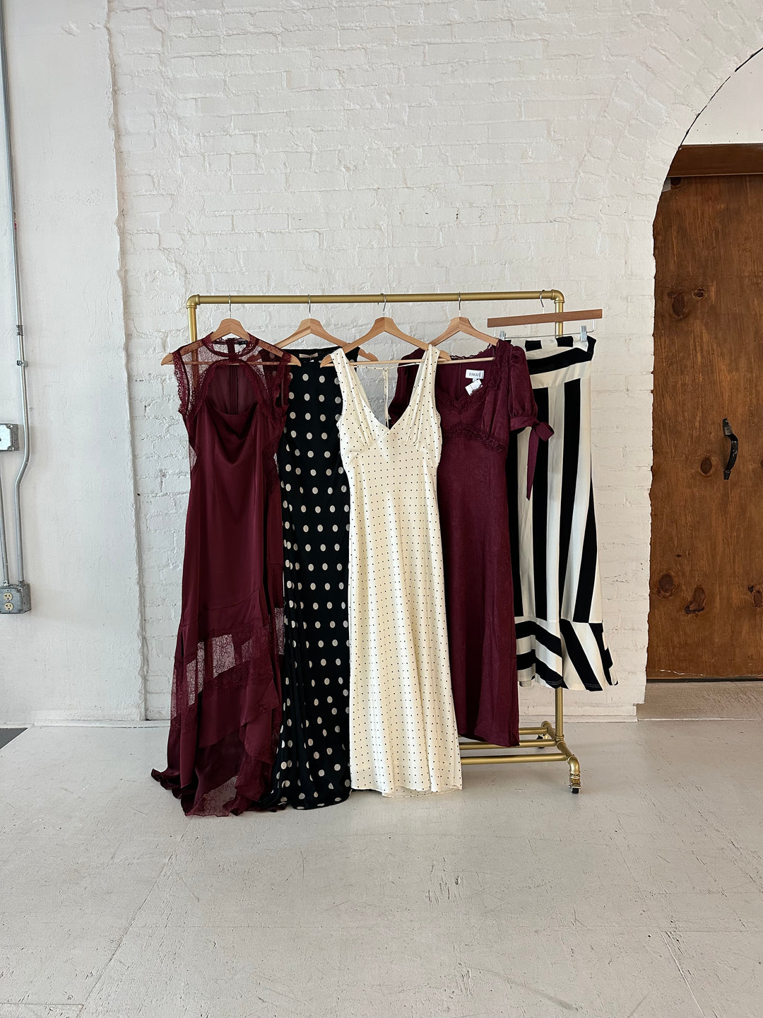 Different burgundy and black formal dresses hanging side by side. 