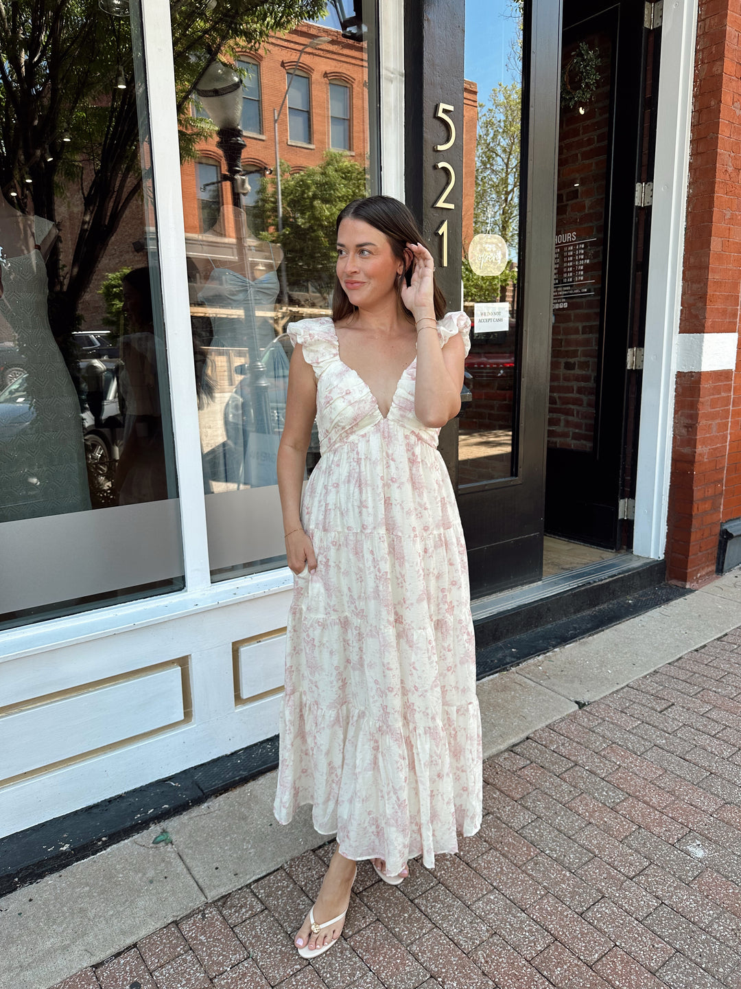 Woman wearing pink floral midi dress with ruched detail along the neckline. 