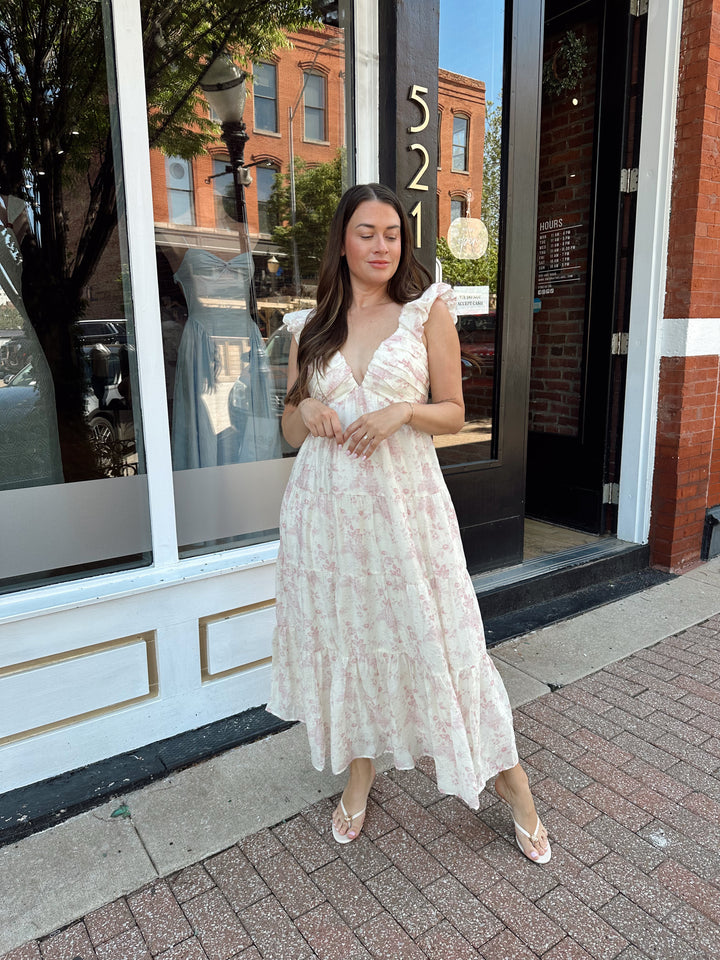Woman wearing pink floral midi dress with ruched detail along the neckline. 