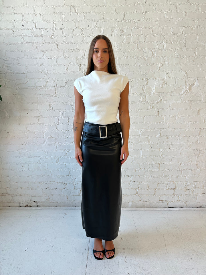 Woman wearing white cap sleeve ribbed sweater top with black faux leather midi skirt. 