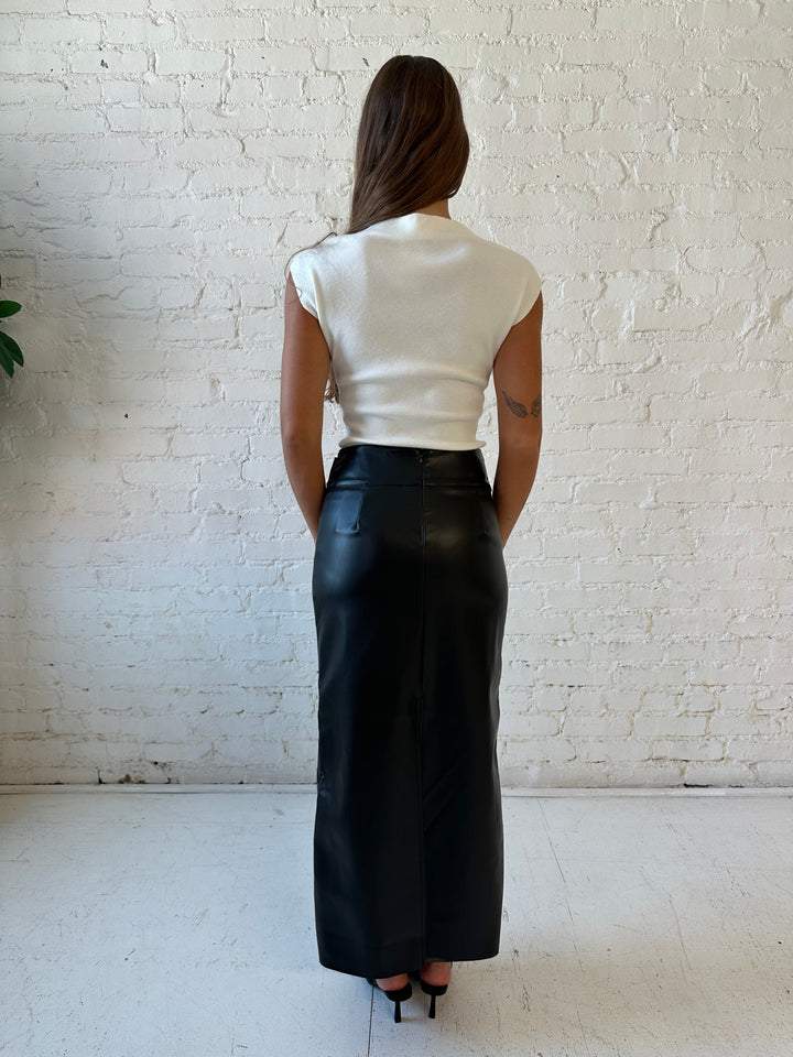 Woman wearing white cap sleeve ribbed sweater top with black faux leather midi skirt. 