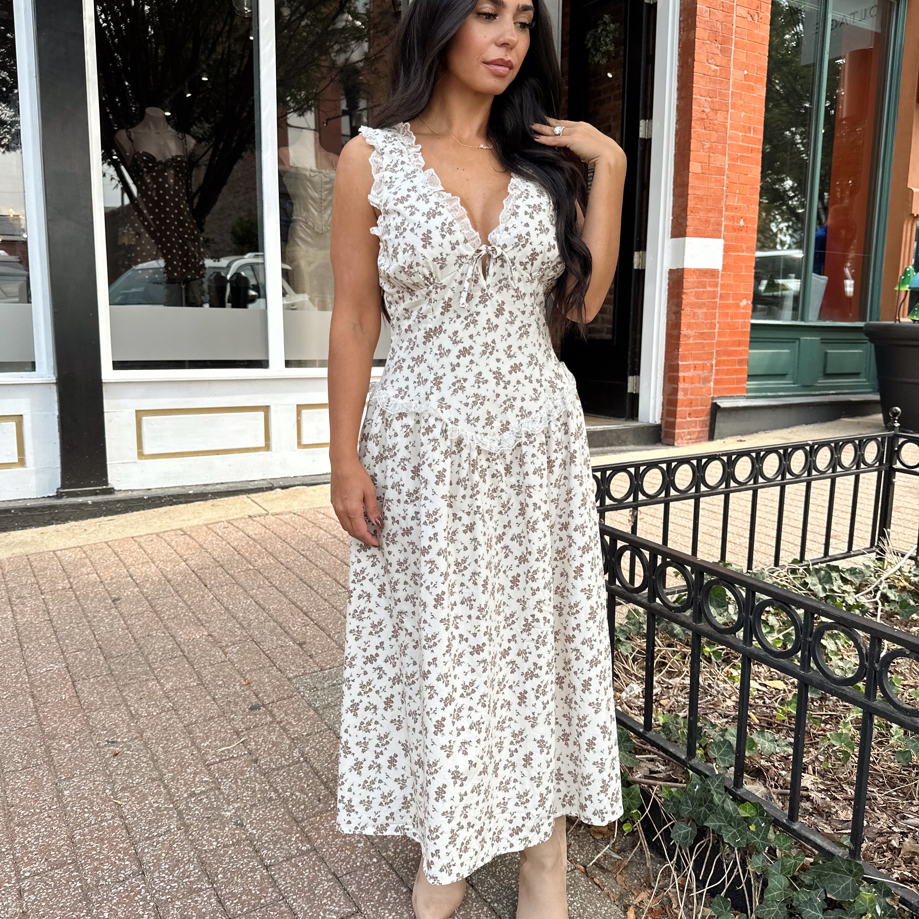 Woman wearing oatmeal midi dress with floral pattern and ruffle detail.