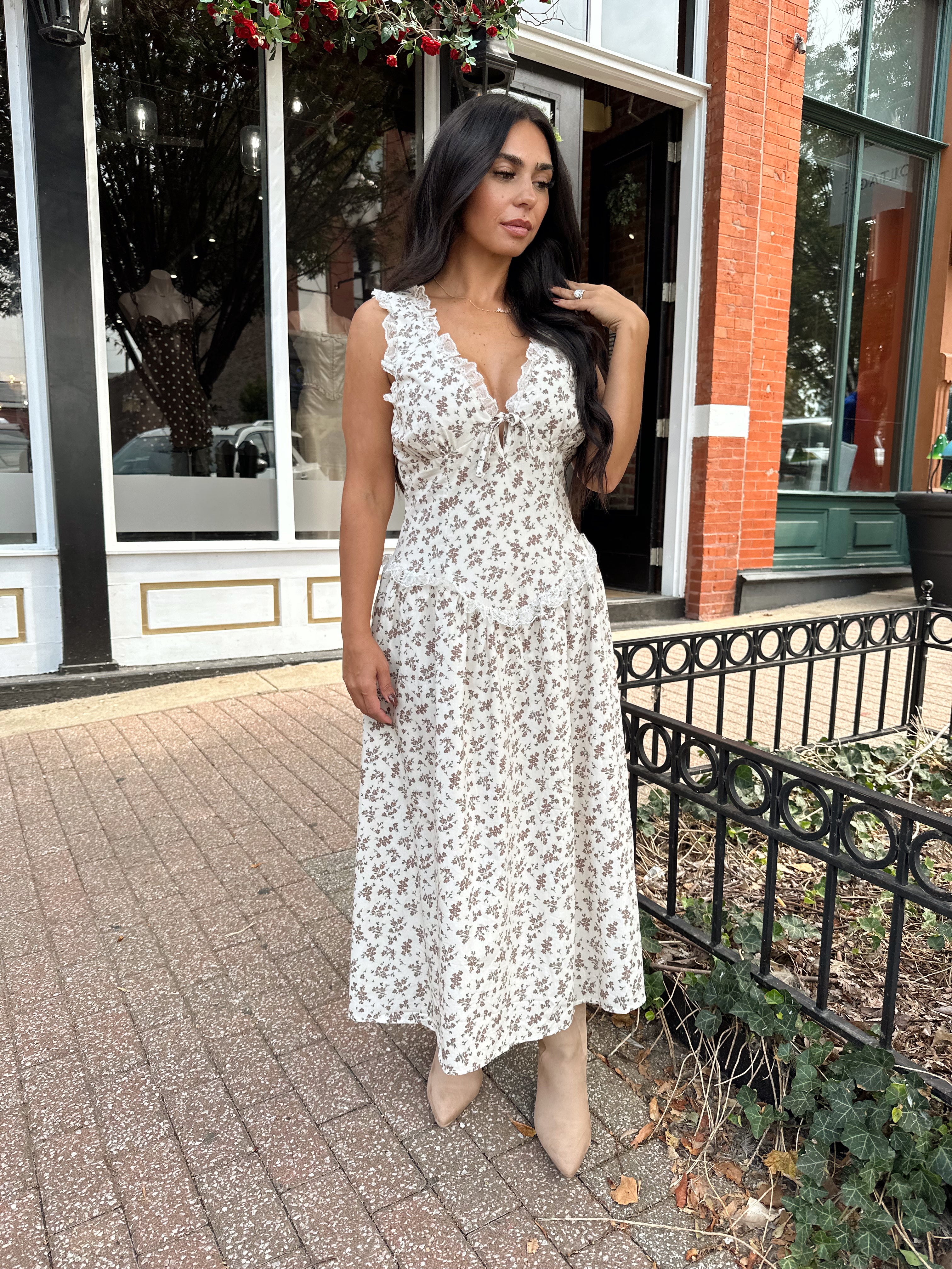 Woman wearing oatmeal midi dress with floral pattern and ruffle detail.