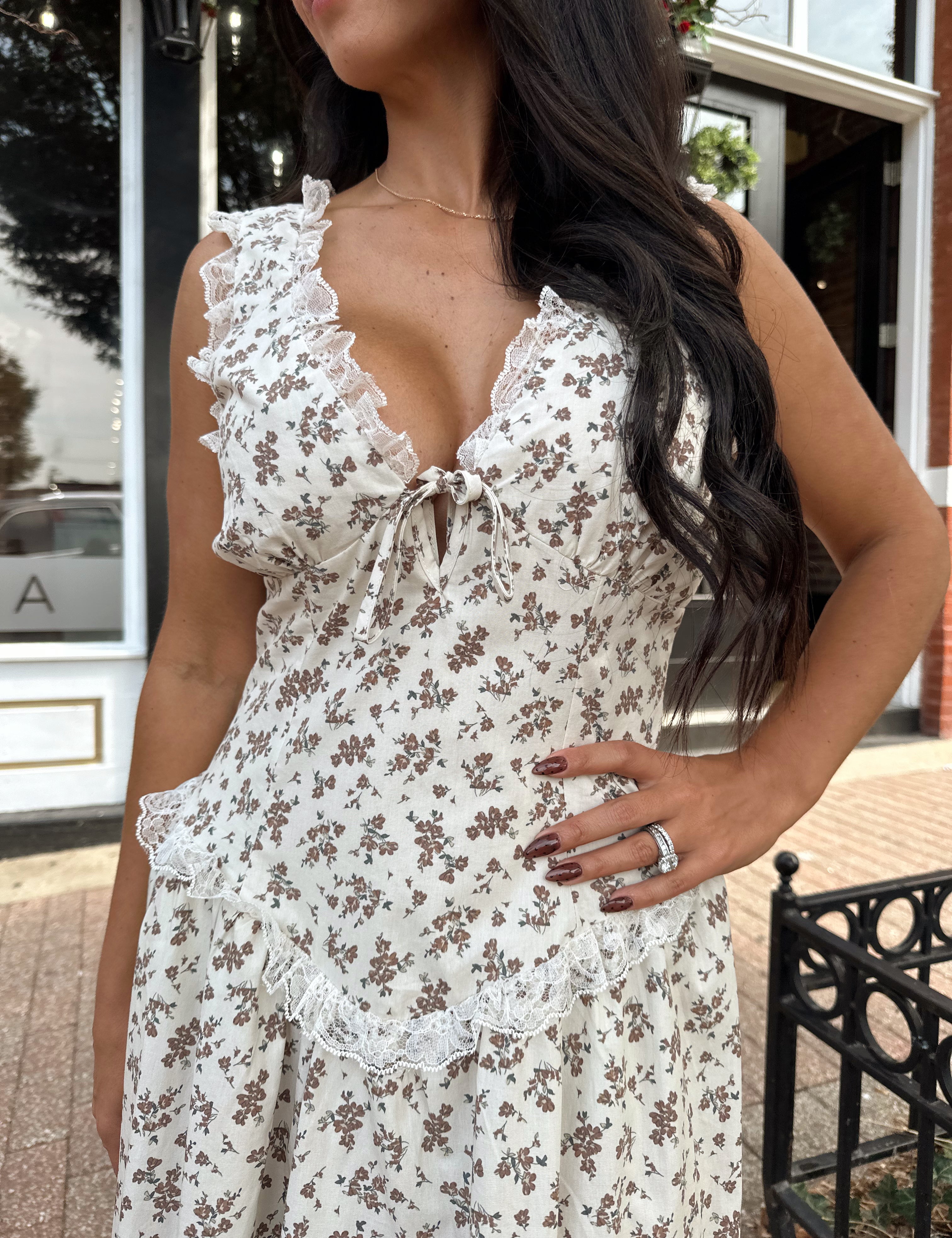 Woman wearing oatmeal midi dress with floral pattern and ruffle detail.