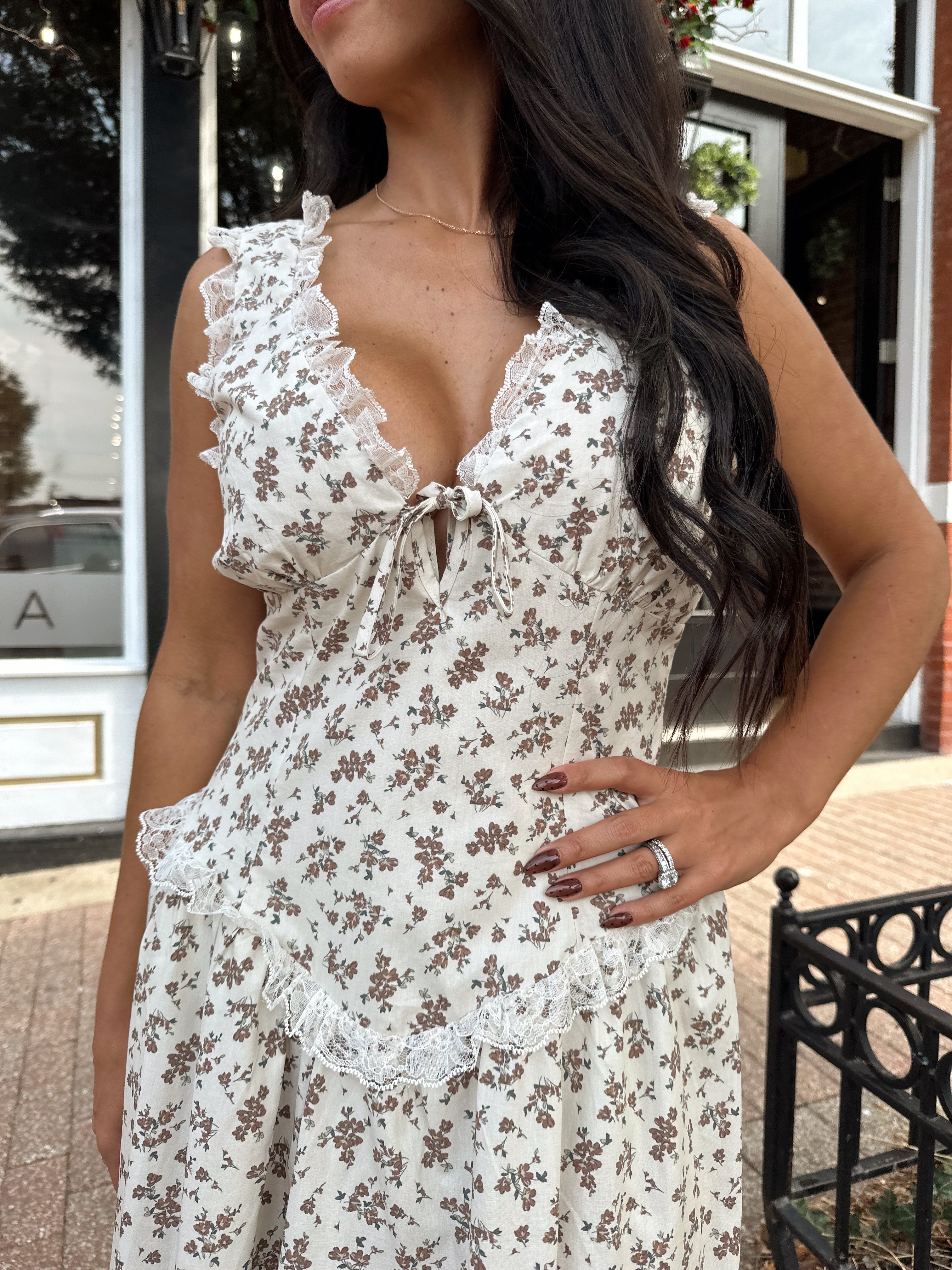 Woman wearing oatmeal midi dress with floral pattern and ruffle detail.
