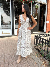 Woman wearing oatmeal midi dress with floral pattern and ruffle detail.