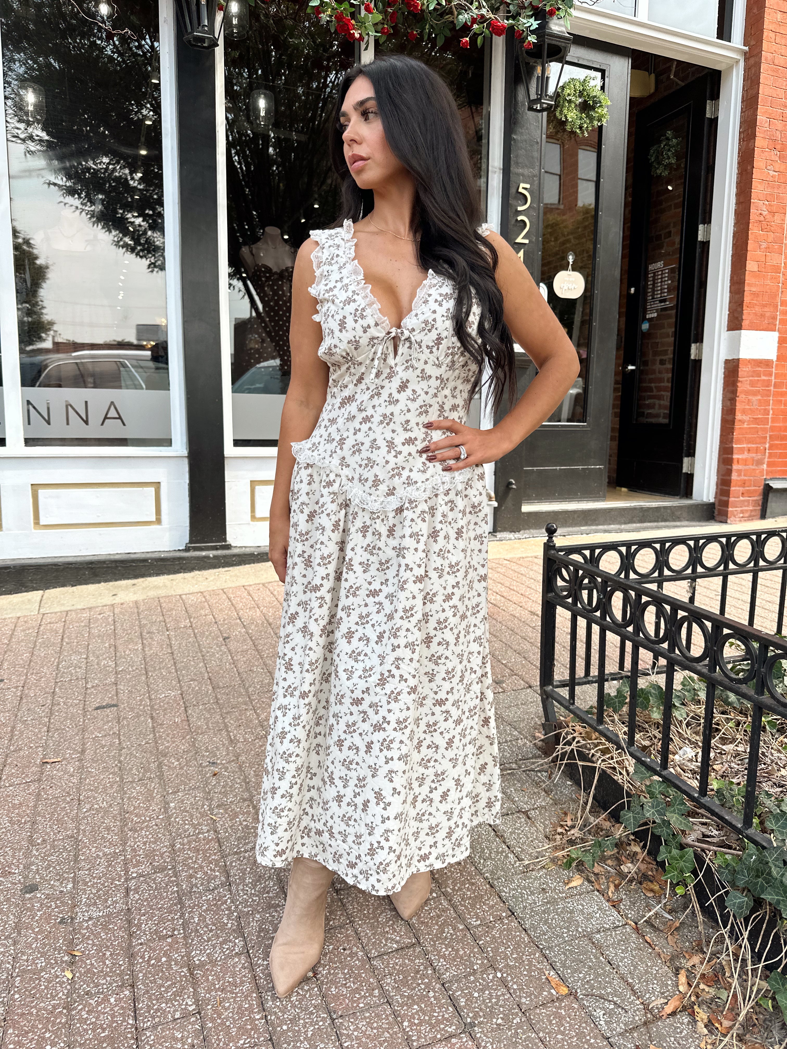 Woman wearing oatmeal midi dress with floral pattern and ruffle detail.