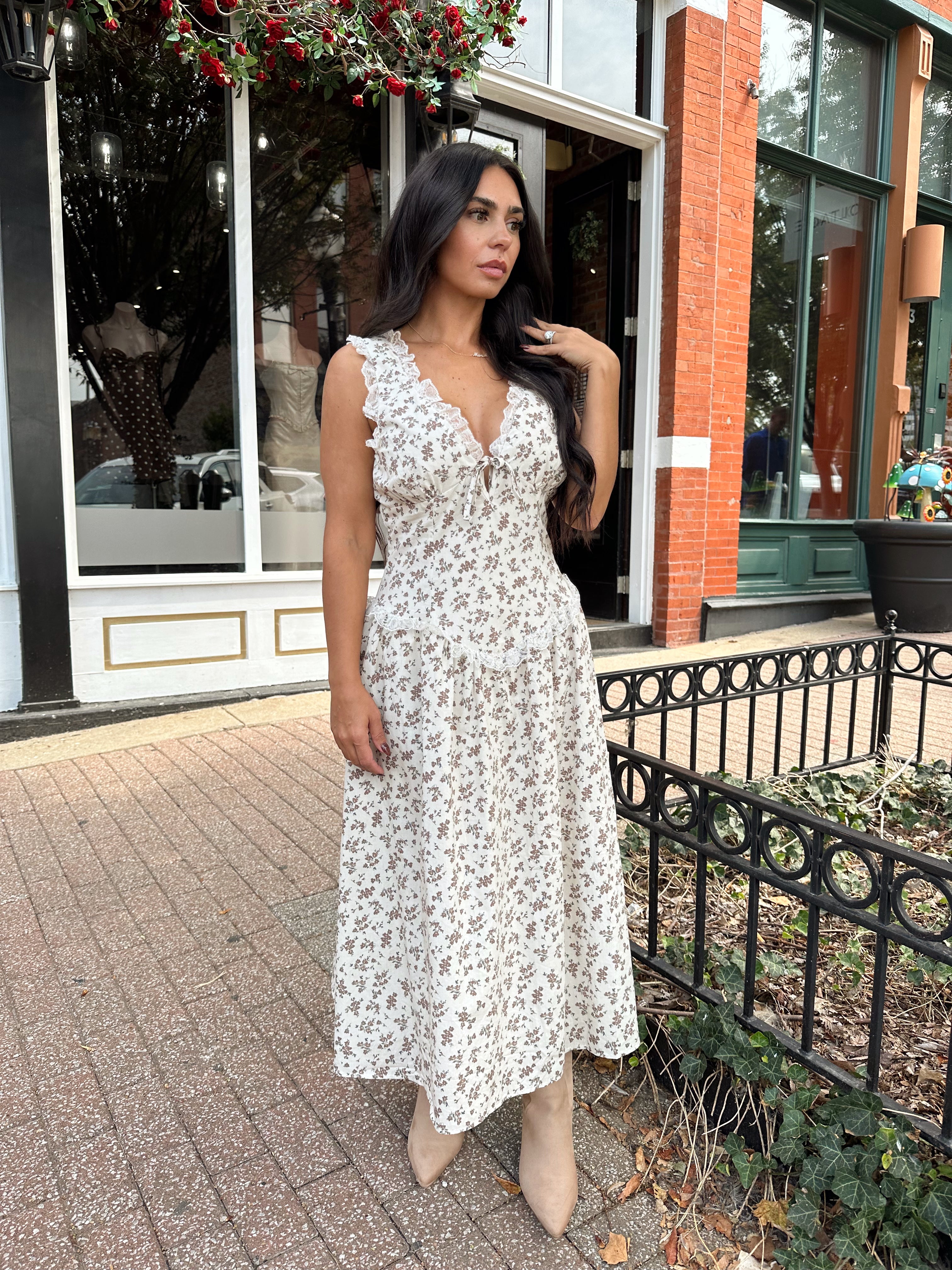 Woman wearing oatmeal midi dress with floral pattern and ruffle detail.