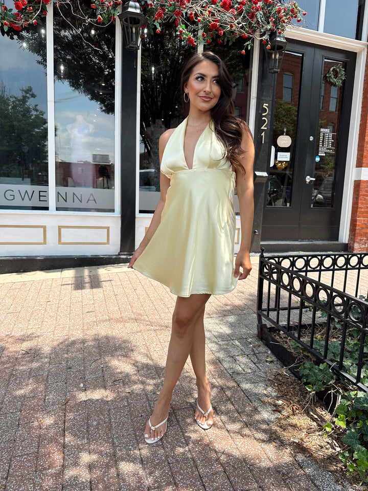 Woman wearing yellow satin halter mini dress.