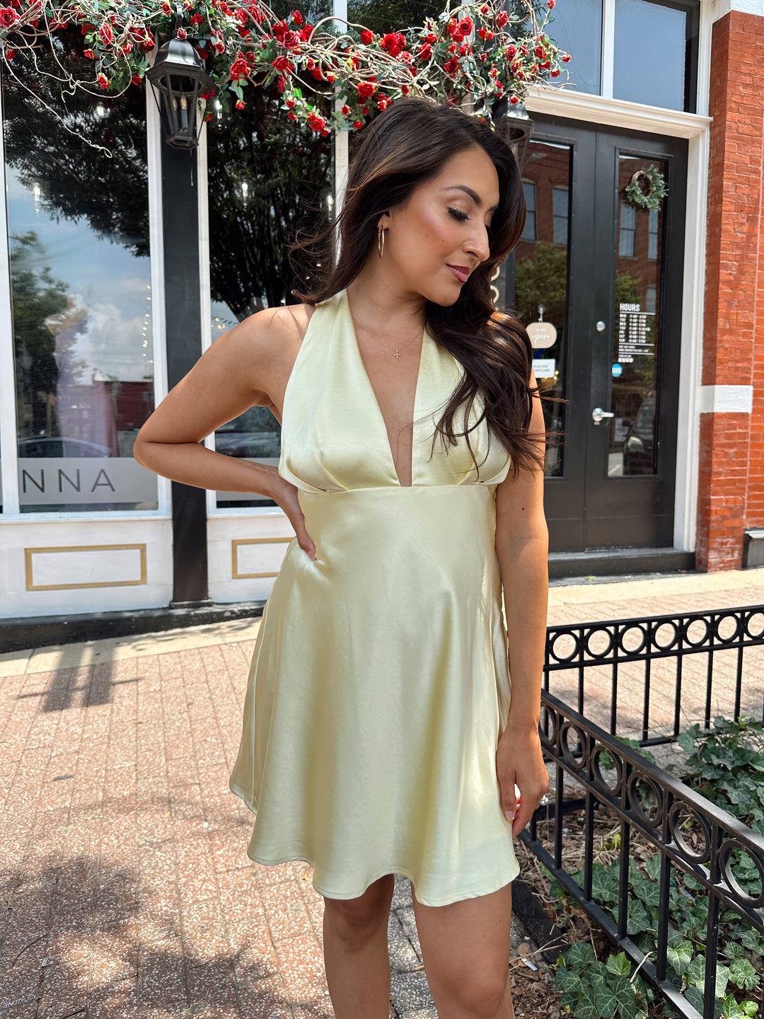 Woman wearing yellow satin halter mini dress.
