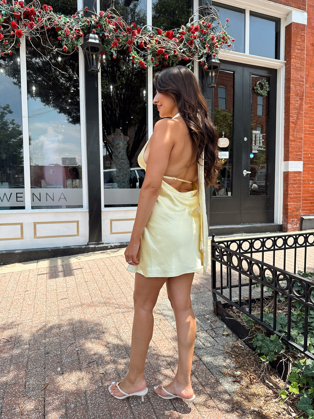 Woman wearing yellow satin halter mini dress.