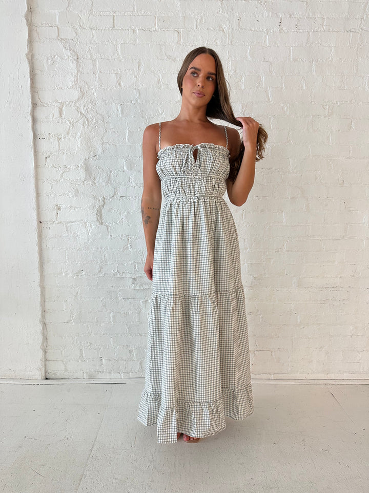 Woman wearing black and white checkered maxi dress with elastic mid section with adjustable straps. 