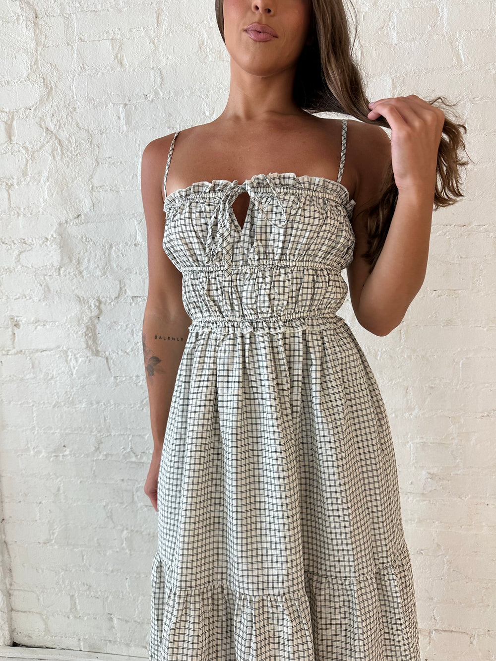 Woman wearing black and white checkered maxi dress with elastic mid section with adjustable straps. 