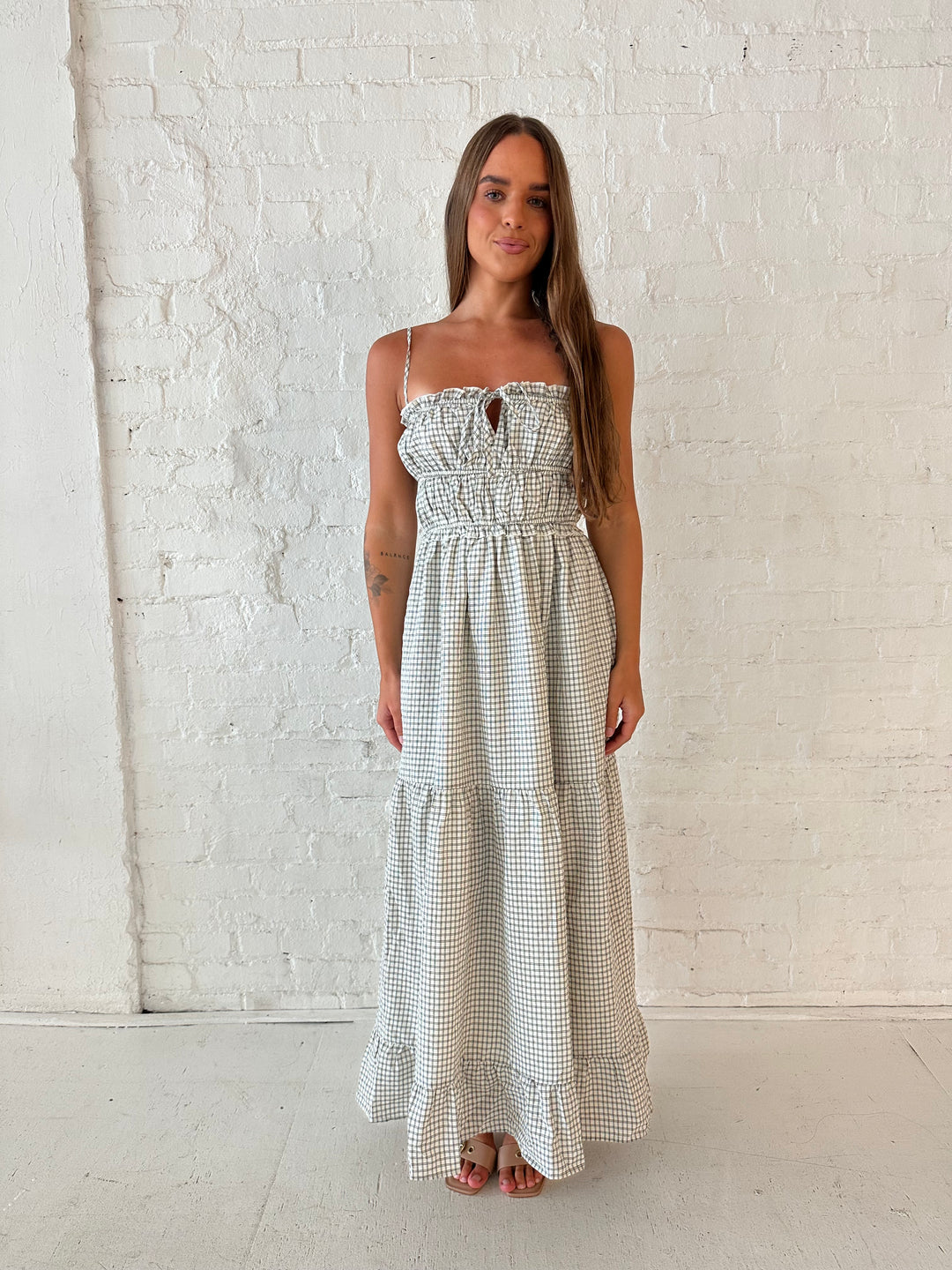 Woman wearing black and white checkered maxi dress with elastic mid section with adjustable straps. 