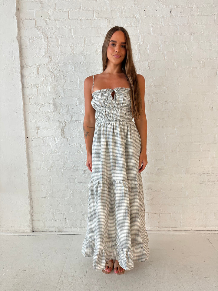 Woman wearing black and white checkered maxi dress with elastic mid section with adjustable straps. 