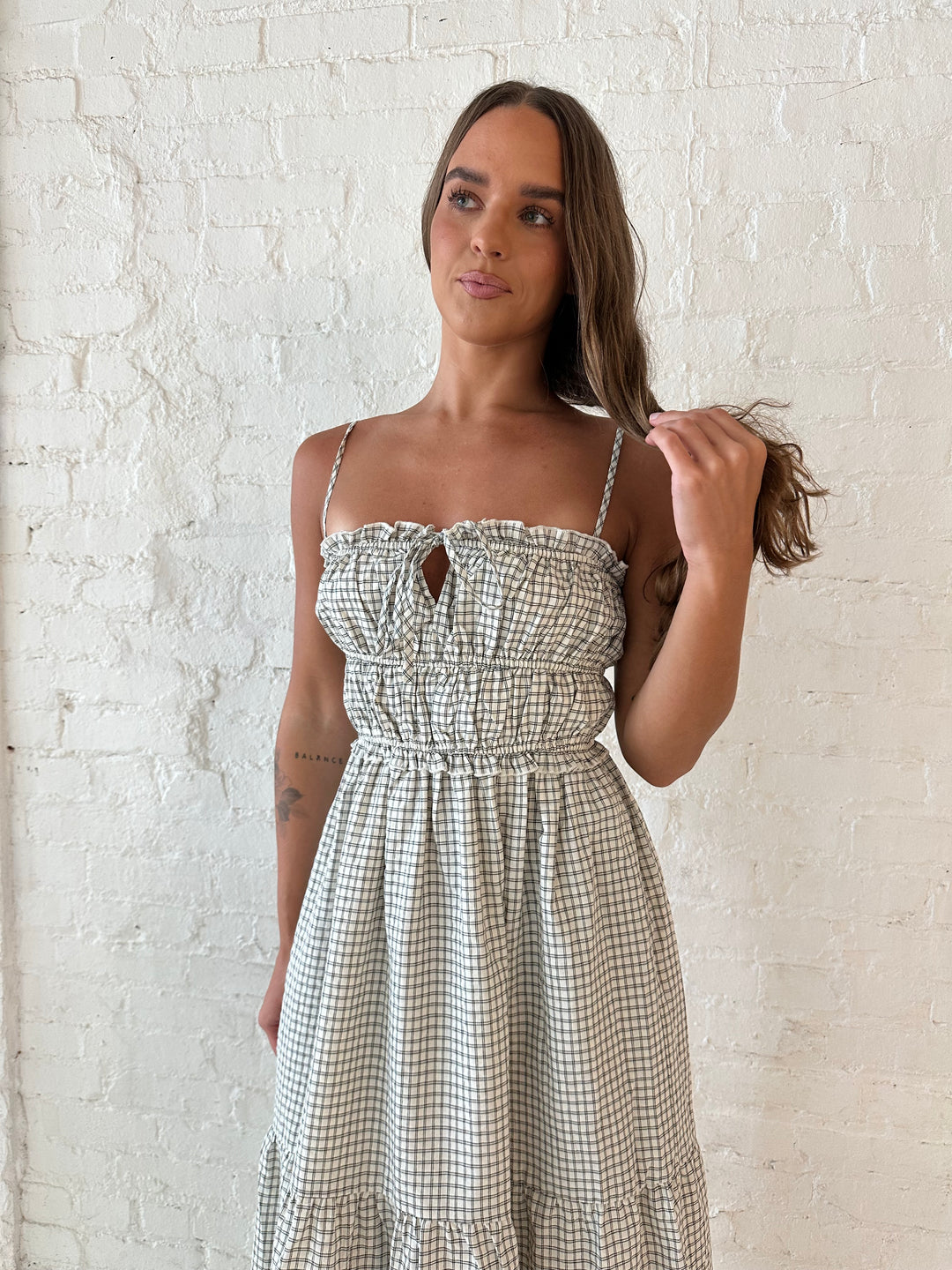 Woman wearing black and white checkered maxi dress with elastic mid section with adjustable straps. 