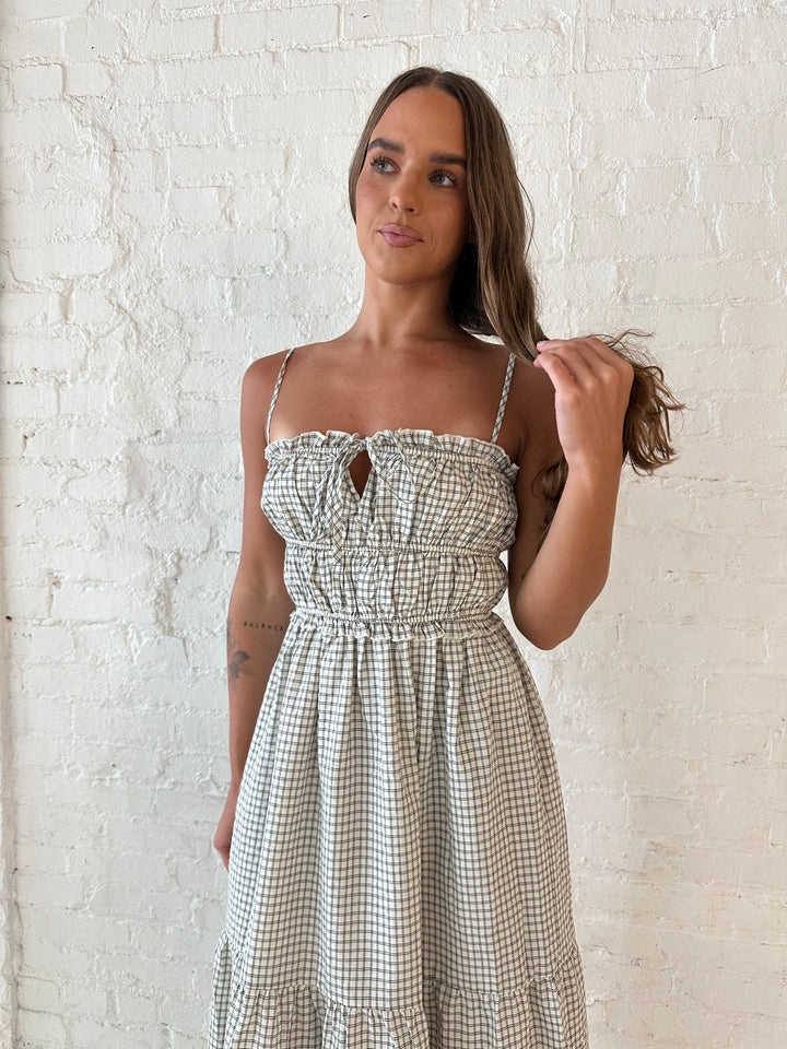Woman wearing black and white checkered maxi dress with elastic mid section with adjustable straps. 