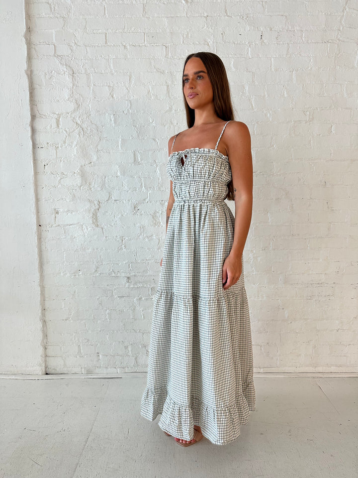 Woman wearing black and white checkered maxi dress with elastic mid section with adjustable straps. 