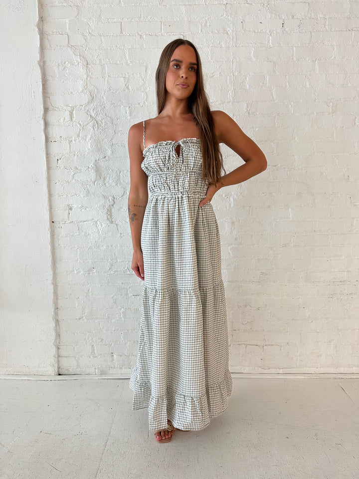 Woman wearing black and white checkered maxi dress with elastic mid section with adjustable straps. 