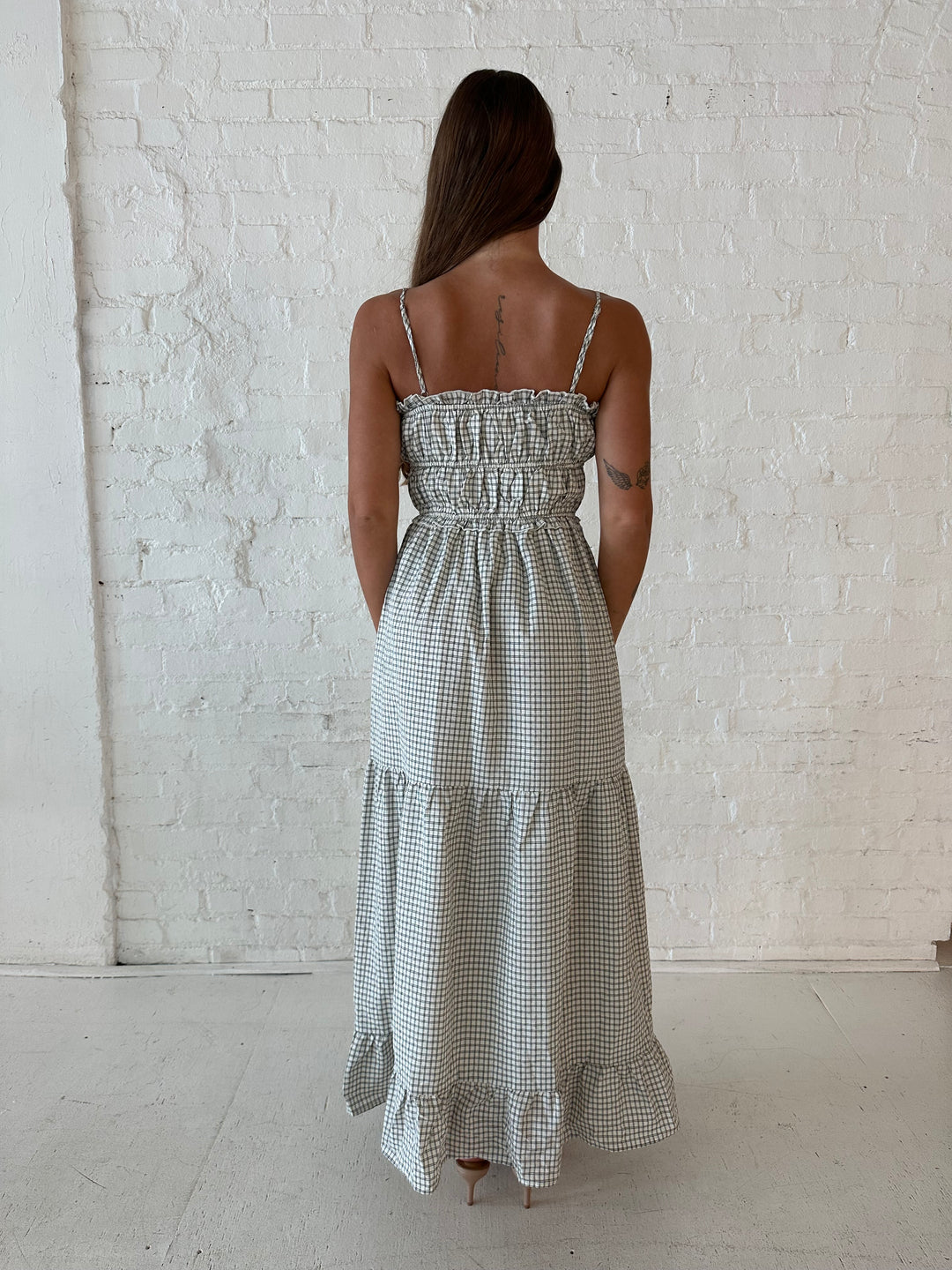 Woman wearing black and white checkered maxi dress with elastic mid section with adjustable straps. 