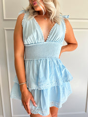 Light blue smocked mini dress with tie straps, lace trim, and tiered skirt