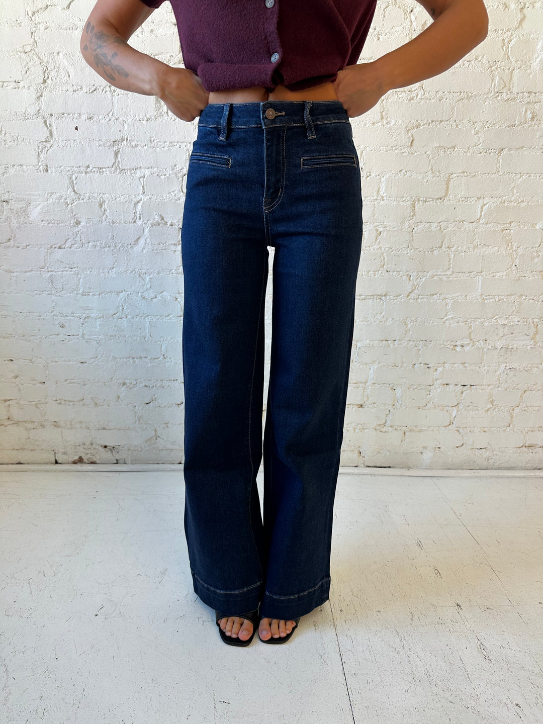 Woman wearing dark wash high waisted, wide leg jeans with sweater top. 